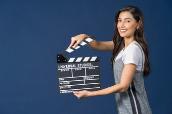 快乐年轻的亚洲女人持有电影场记板工作室设置电影蓝色的颜色背景广播和生产商电影和电影减少概念