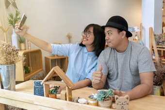 亚洲年轻的夫妇采取的自拍与幸福行动现代咖啡商店工作场所联合办公空间现代办公室生活方式和休闲概念