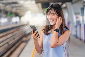 亚洲女人使用脸<strong>识别</strong>通过聪明的移动电话和听的音乐铁路站平台生物<strong>识别</strong>验证和人工情报概念