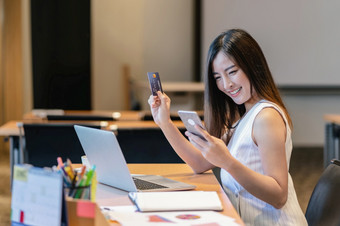 亚洲女商人休闲西装做在线购物使用信贷<strong>卡</strong>和支付通过聪明的移动<strong>电话</strong>应用程序技术移动PC现代办公室业务和生活方式概念