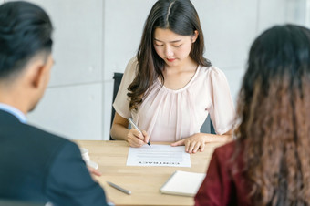 年轻的亚洲女人签署的合同与两个经理与积极的运动会议房间业务招聘新成员工作面试协议标志合同与经理概念
