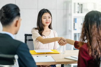 年轻的亚洲女人研究生手摇与两个经理欢迎之前开始工作面试与积极的运动会议房间业务招聘新成员工作面试第一个印象概念