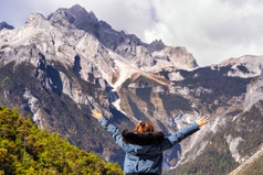 后视图亚洲女人旅行者提高两个手在的玉龙雪山背景蓝色的月亮谷玉龙雪山丽江云南中国旅行和旅游概念