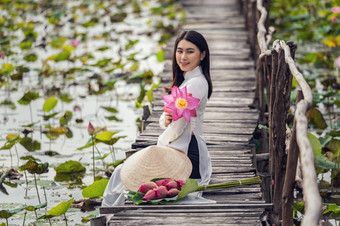 肖像美丽的越南女人与传统的越南他持有的粉红色的莲花坐着的木桥大莲花湖越南爱山东南亚洲旅行概念
