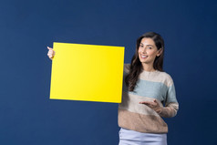 快乐年轻的微笑亚洲女人持有和展示复制空间空黄色的广告牌蓝色的颜色背景思考和染斑通过气球空白纸广告概念