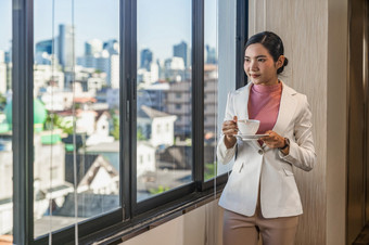 亚洲女商人休闲西装站与咖啡<strong>打破</strong>旁边的窗口<strong>玻璃</strong>业务和生活方式概念