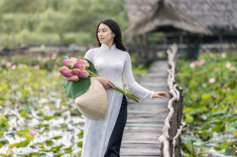 肖像美丽的越南女人与传统的越南他持有的粉红色的莲花走的木桥大莲花湖越南爱山东南亚洲旅行概念