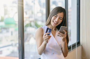 亚洲女商人休闲西装做在线购物使用信贷卡和支付通过聪明的移动电话应用程序技术移动PC现代办公室业务和生活方式概念