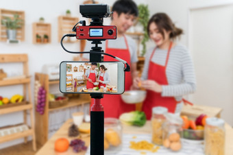 特写镜头聪明的移动电话采取生活快乐亚洲情人夫妇烹饪的厨房房间相机为摄影师视频和生活流媒体概念