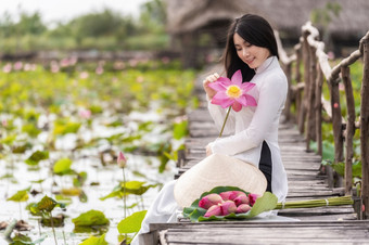 肖像美丽的<strong>越南</strong>女人与传统的<strong>越南</strong>他持有的粉<strong>红</strong>色的莲花坐着的木桥大莲花湖<strong>越南</strong>爱山东南亚洲旅行概念