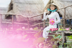 肖像美丽的越南女人与传统的越南他持有的粉红色的莲花的木桥大莲花湖越南爱山东南亚洲旅行概念