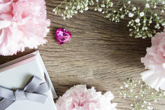 粉红色的心与礼物盒子和康乃馨花木背景