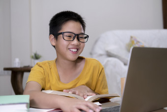 高高兴兴地男孩兴奋使用电脑在线学习家庭作业亚洲男孩享受自我研究与电子学习首页在线教育和自我研究和在家教育概念
