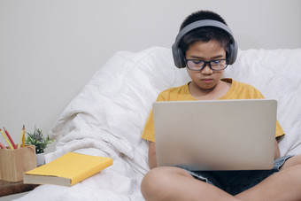 高高兴兴地男孩兴奋使用电脑在线学习家庭作业亚洲男孩享受自我研究与电子学习首页在线教育和自我研究和在家教育概念