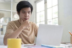 年轻的男人。使用移动PC为工作从首页办公室使用在线连接技术为业务教育和沟通