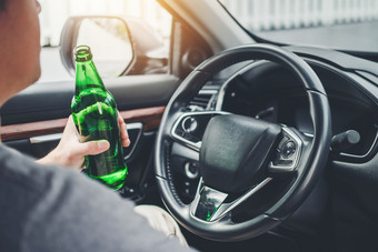 喝醉了男人。开车车的路持有瓶啤酒危险的喝醉了开车概念