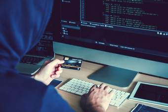 危险的连帽黑客使用信贷卡打字坏数据成电脑在线系统和传播全球偷来的个人信息网络安全概念