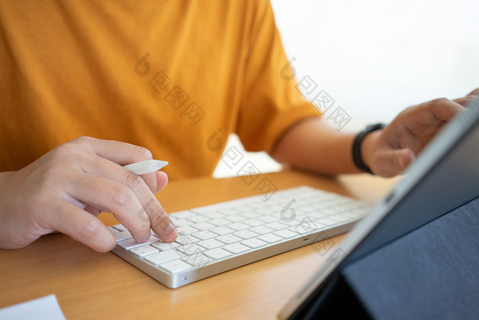 年轻的自由职业者商人工作首页办公室和打字键盘智能手机平板电脑工作在线研究和学习而使用智能手机平板电脑自由工作业务概念