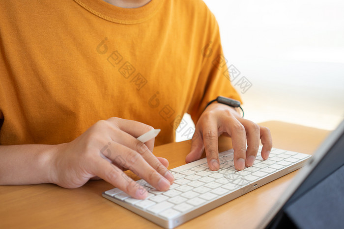 年轻的自由职业者商人工作首页办公室和打字键盘智能手机平板电脑工作在线研究和学习而使用智能手机平板电脑自由工作业务概念