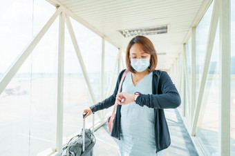 女人穿脸面具旅行的机场新生活方式旅行后新冠病毒社会距离和旅行泡沫概念