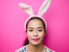 可爱的十几岁的女孩穿兔子耳朵头巾和粉红色的背景女人穿兔子耳朵头巾在复活节有吸引力的年轻的女人和微笑明亮的粉红色的背景