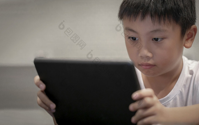 亚洲男孩玩游戏数字平板电脑首页孩子们看漫画数字taplet智能手机