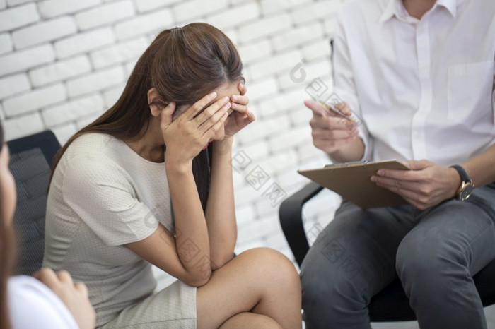 沮丧年轻的业务女人和不开心持有头手心理治疗会话精神病学家使笔记日记工作办公室