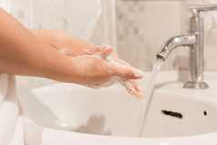 年轻的女人洗手摩擦与肥皂预防为冠状病毒关闭