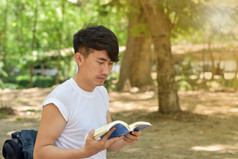 肖像年轻的男人。阅读书的公园夏天一天