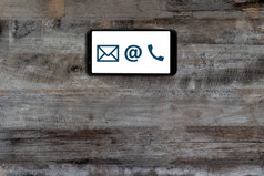 联系智能手机显示图标电话邮件地址木桌子上背景