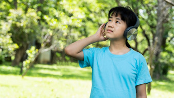 肖像年轻的女孩听音乐与现代耳机公园在户外13岁以下的女孩享受节奏听音乐与耳机无线