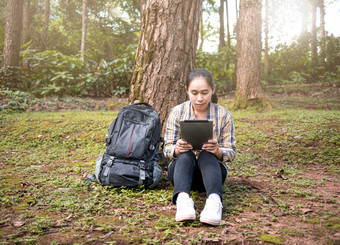 年轻的女人旅行者搜索全球定位系统(gps)坐标平板电脑自然小道夏天假期一天技术和旅行概念