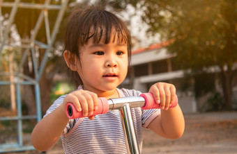 可爱的<strong>小孩</strong>子女孩有有趣的骑踏板车路<strong>夏天</strong>公园概念快乐家庭和童年