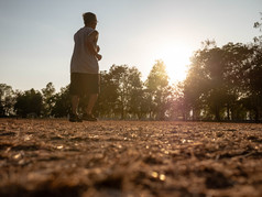 亚洲高级男人。慢跑的公园在日落天空背景健康的生活方式和医疗保健概念