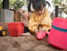 快乐小孩子女孩有有趣的玩与塑料玩具坐着的沙盒阳光明媚的夏天一天