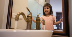 快乐亚洲小孩子女孩刷牙牙齿的浴室早....口服卫生概念