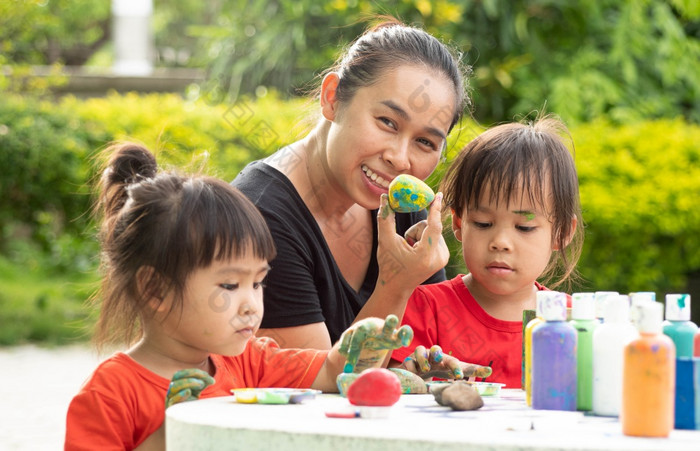 亚洲两个小姐妹享受与手绘丙烯酸油漆石头和木块与她的妈妈。热夏天一天孩子们rsquo创造力工艺品