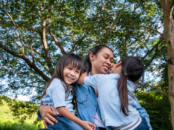 两个兄弟姐妹小女孩与<strong>妈妈</strong>笑和拥<strong>抱</strong>每一个其他温暖的和阳光明媚的夏天一天的花园年轻的女孩与她的<strong>妈妈</strong>。支出一天公园