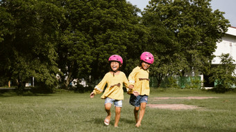 两个可爱的<strong>小姐妹</strong>头盔运行的草坪上公园阳光明媚的夏天一天采取打破后骑自行车实践快乐童年家庭支出时间在一起