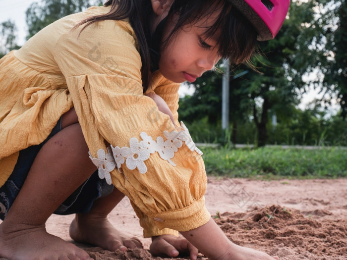 可爱的小女孩头盔是玩与沙子公园阳光明媚的夏天一天采取打破后骑自行车实践开发想象力和探索