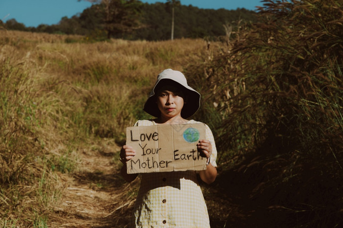 肖像拍摄亚洲年轻的女生态acivist站热带森林有被摧毁了为玉米种植园和持有海报与单词爱你的妈妈。地球手气候改变凹陷