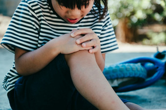 伤心小女孩坐着的地面后下降从她的自行车夏天公园孩子是受伤的而骑自行车