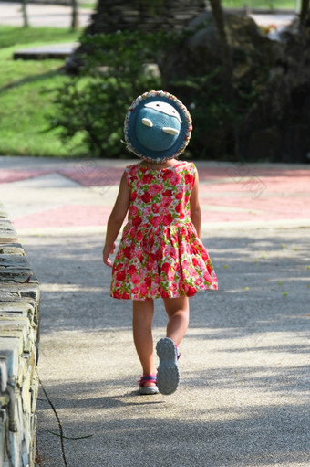 可爱的微笑小女孩红色的花衣服走和有有趣的的绿色草的公园童年概念