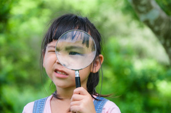 可爱的小女孩学习和探索自然与户外放大玻璃好奇的孩子看起来通过放大玻璃树的公园小女孩玩与放大玻璃