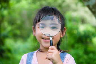 可爱的小女孩学习和探索自然与户外放大玻璃好奇的孩子看起来通过放大玻璃树的公园小女孩玩与放大玻璃