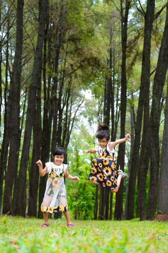 快乐孩子们玩的绿色草的春天花园两个小姐妹是运行草地夏天公园