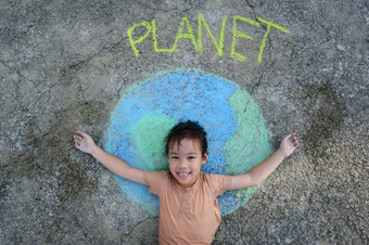 可爱的小女孩说谎美丽的世界绘画与粉笔标签地球沥青年轻的志愿者活动保存的世界在户外概念世界环境一天和和平一天