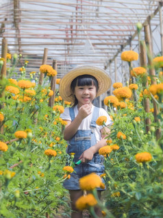 小女孩穿他帮助她的妈妈。的金盏花花园小园丁可爱的女孩玩美丽的花花园