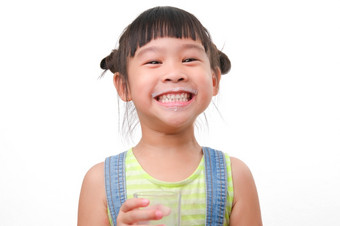 肖像可爱的亚洲小女孩持有玻璃牛奶孤立的白色背景小女孩首页与微笑脸感觉快乐享受喝牛奶和看相机