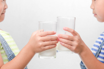 两个小姐妹喝美味的牛奶从眼镜孤立的白色背景快乐和岁姐妹喝健康的牛奶之前学校